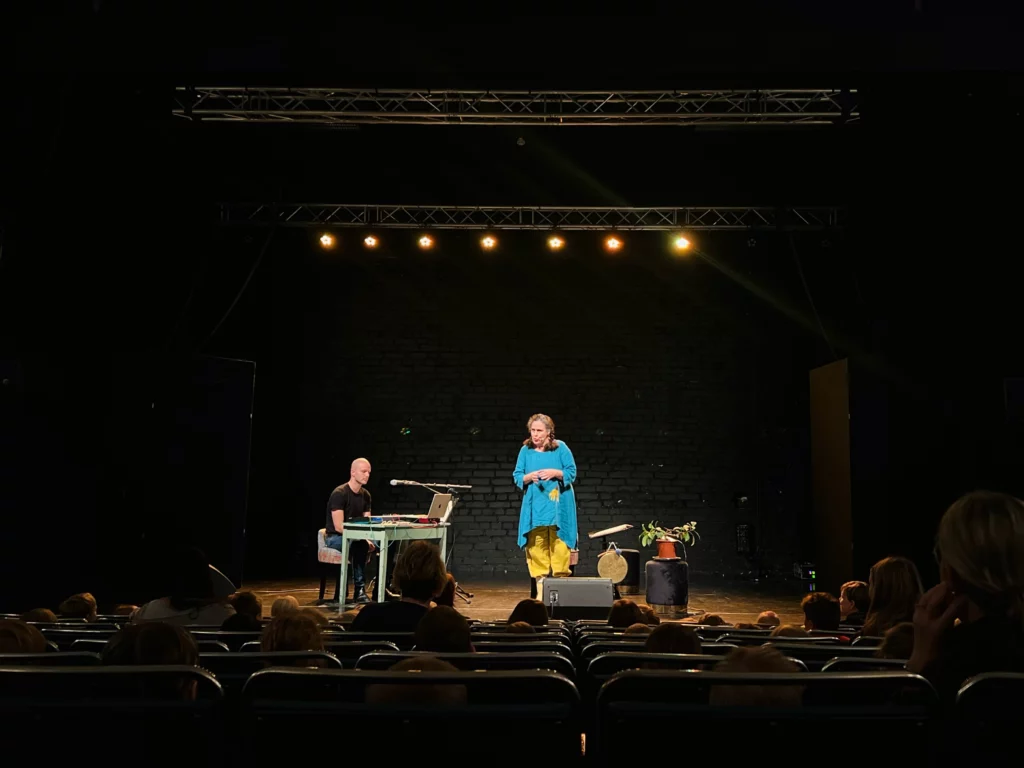 Två konstnärer står på Karelias scen framför en barnpublik
