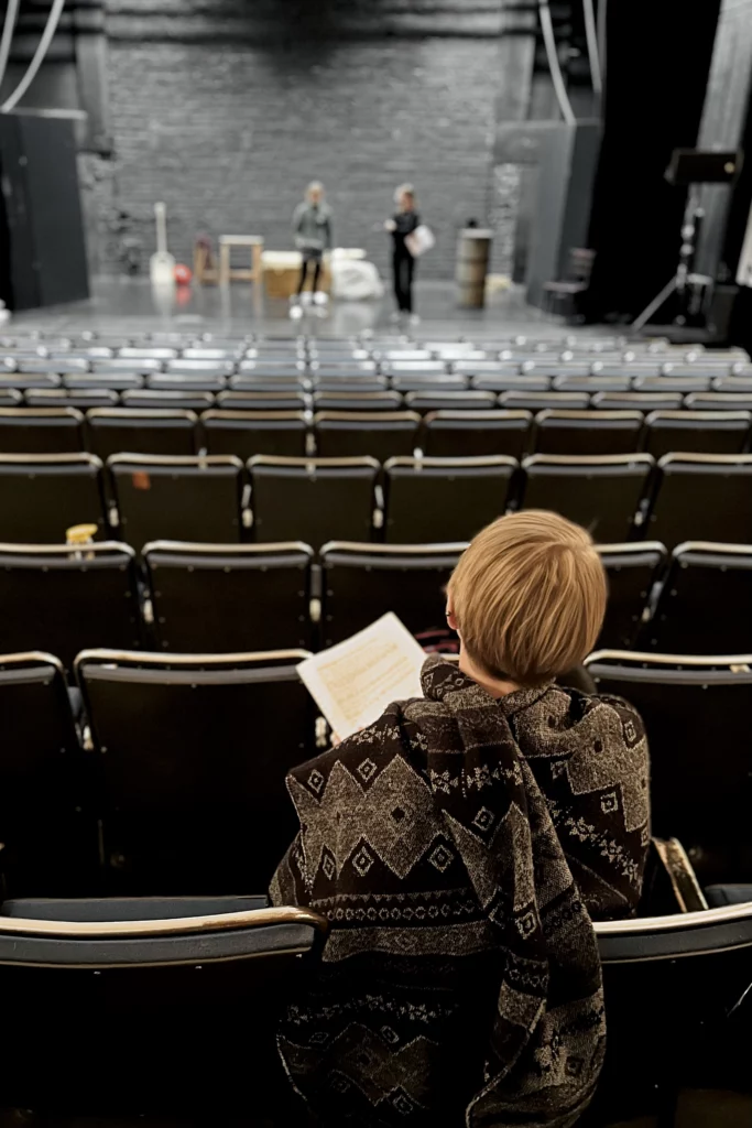 En regissör sitter i Karelias sal och ser på två personer som står på scenen.

Ohjaaja istuu Karelian salissa ja katsoo kahta näyttämöllä olevaa henkilöä.